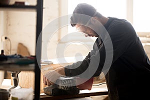 Serious skilled carpenter working using sander for grinding wood