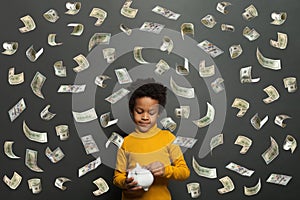 Serious smart little boy on falling us dollar money rain on black background