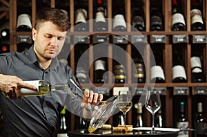 Serious sommelier pouring white wine in decanter