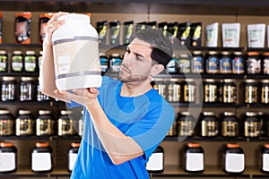 Serious sportman looking different sport nutrition products photo