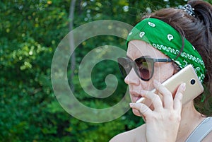 Serious stressed girl speaking on cellphone in park. Frowning young woman in casual calling on mobile phone, listening and staring