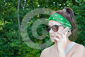 Serious stressed girl speaking on cellphone in park. Frowning young woman in casual calling on mobile phone, listening and staring