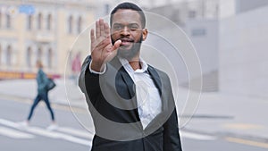 Serious strong decisive African bearded young adult ethnic male puts palm in front of him, confidently shows stop