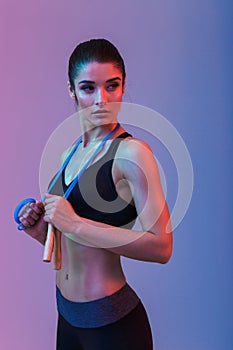 Serious strong young sports woman holding skipping rope.