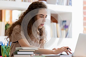 Serious student girl studying using laptop sitting at classroom desk