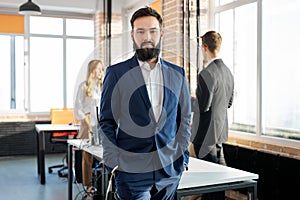 serious successful male in suit looks at camera, portrait in office