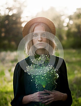 Serious sunny portrait of a stylish girl in a straw hat with a