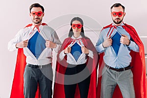 serious super businesspeople in masks and capes showing blue shirts