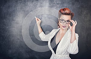 Serious teacher in glasses on the blackboard background