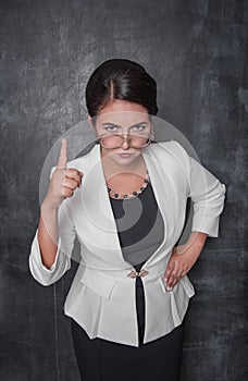 Serious teacher looking at you on blackboard