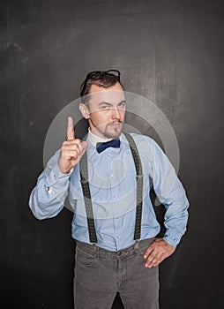 Serious teacher man threaten by finger on blackboard