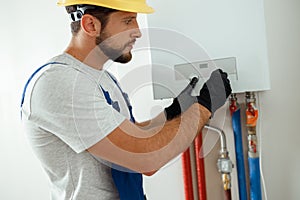 Serious technician setting the new gas boiler for hot water and heating