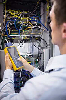 Serious technician using digital cable analyzer on server