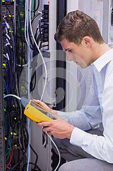 Serious technician using digital cable analyzer on server