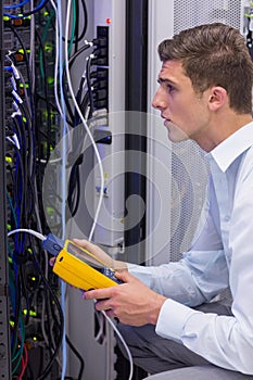 Serious technician using digital cable analyzer on server