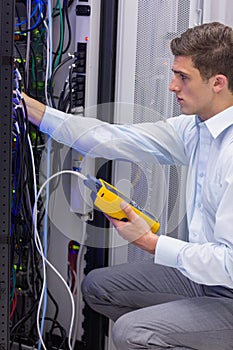 Serious technician using digital cable analyzer on server