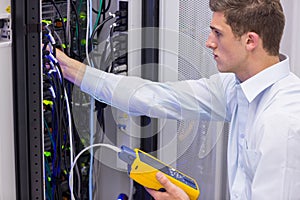 Serious technician using digital cable analyzer on server