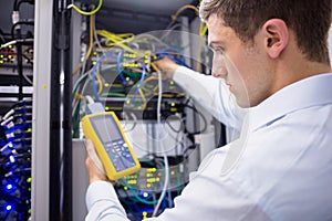 Serious technician using digital cable analyzer on server