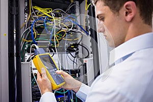 Serious technician using digital cable analyzer on server