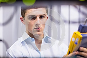 Serious technician using digital cable analyzer on server