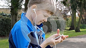 Serious teen boy with smart phone listening or talking in british park. teenager and social media concept