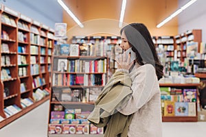 Serious teen gen Z Korean student girl holding mobile phone, using app on smartphone in college library, browsing, chatting,