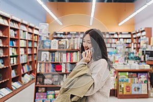 Serious teen gen Z Korean student girl holding mobile phone, using app on smartphone in college library, browsing, chatting,