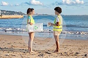 Serious teenager different children volunteers in vests collect garbage in ocean on beach, for recycling, full length