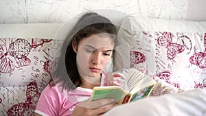 Serious teenager with long hair in ponytail reads book