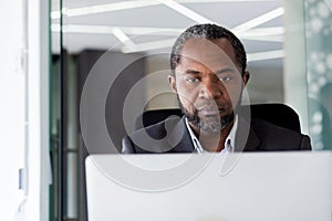 Serious thinking boss businessman close up, african american man working with laptop, man reading from computer screen