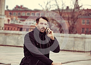 Serious thinking business man in fashion clothing talking on mobile phone on outdoors autumn background. Closeup