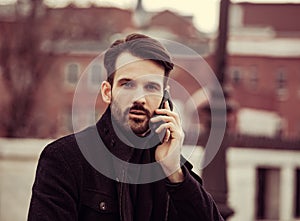 Serious thinking business man in fashion clothing talking on mobile phone on outdoors autumn background. Closeup