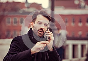 Serious thinking business man in fashion clothing talking on mobile phone on outdoors autumn background. Closeup