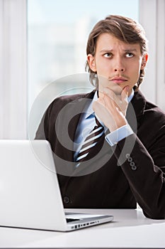 Serious thinking business man with laptop