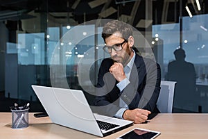 Serious thinking businessman working inside office building, man pondering important decision, boss in business suit