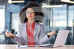 Serious thinking woman meditating relaxing in lotus position inside office, business woman with closed eyes sitting at