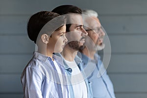 Serious thoughtful boy kid standing in row with young fath