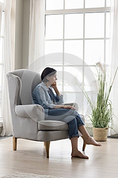 Serious thoughtful lonely mature lady sitting in armchair at home