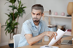 Serious thoughtful man holding papers thinking of problem solution