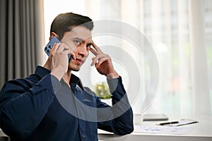 Serious and thoughtful millennial Asian businessman having a serious phone call with his client