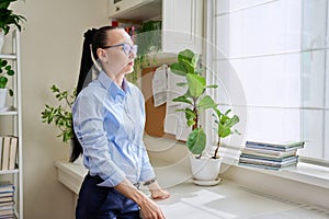 Serious thoughtful woman in her 30s looking out the window