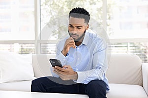 Serious thoughtful young African man using financial service