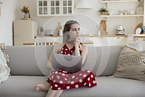Serious thoughtful young freelancer girl working with laptop