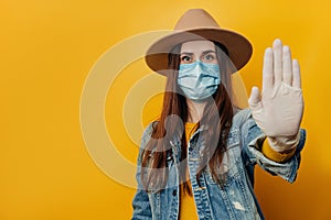 Serious traveler tourist woman in medical sterile face mask gloves, showing stop gesture