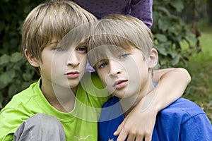 Serious twins hugging in park