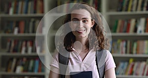 Serious university student girl with backpack posing in college library