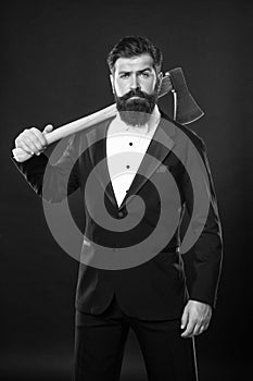 Serious unshaven man with beard and moustache in formal suit holding axe dark background, brutal