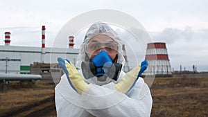 Serious virologist man in protective suit and respirator saying no by crossed his arms in X sign