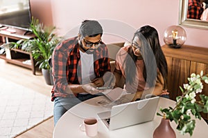 Serious wife and husband planning budget, checking finances, focused young woman using online calculator and counting