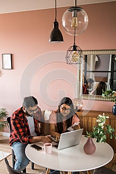Serious wife and husband planning budget, checking finances, focused young woman using online calculator and counting